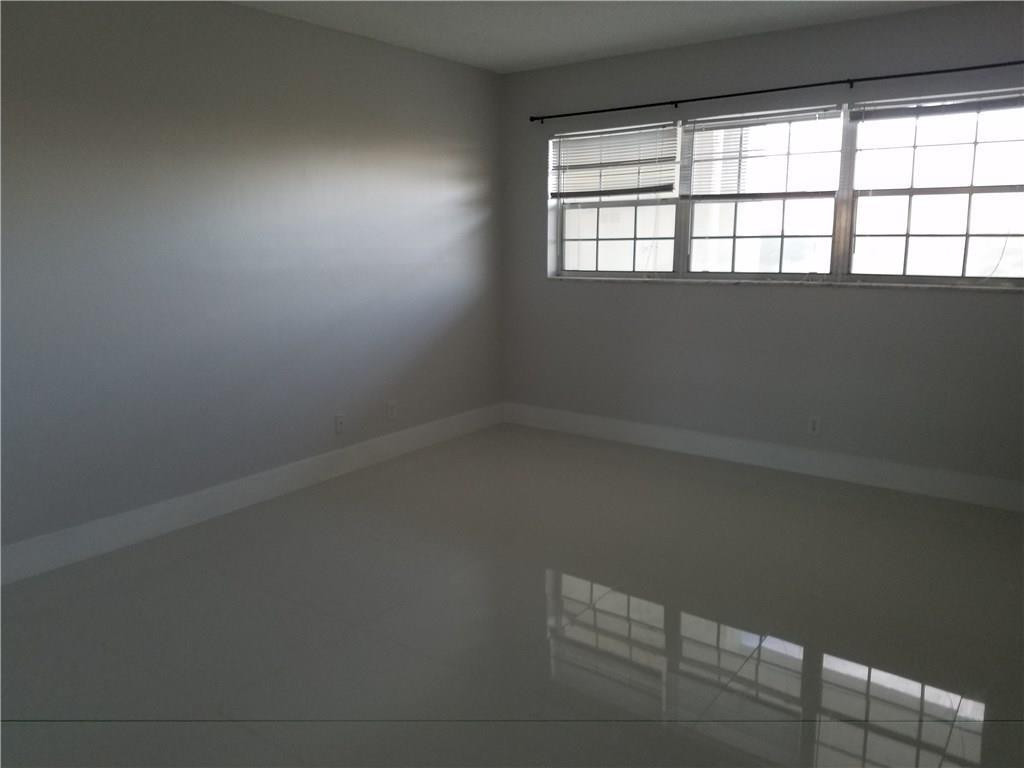 3150 North Course Lane, Unit 607 Pompano Beach, FL 33069 - Photo 6 of 16 wooden floor in an empty room with a window