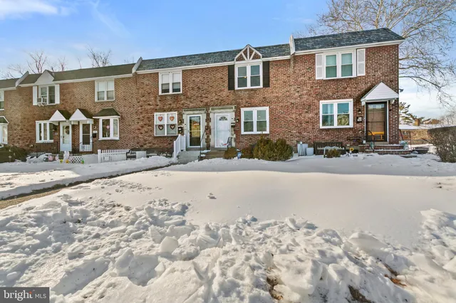 front view of a house with a snow on the road