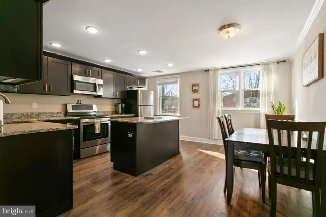 a kitchen with stainless steel appliances granite countertop a stove a sink a microwave a dining table and chairs