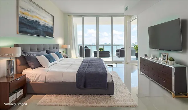 a bedroom with a large bed and a flat tv screen on dresser