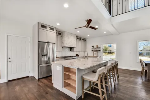 a kitchen with stainless steel appliances a stove a refrigerator a dining table and chairs with wooden floor