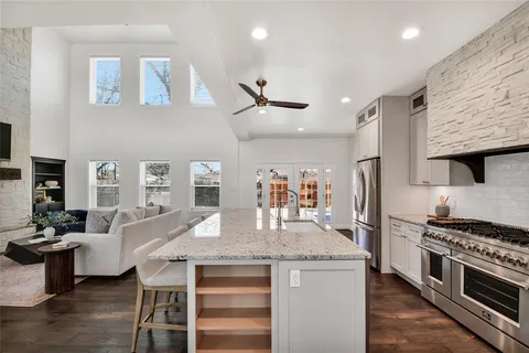 a kitchen with granite countertop a stove a sink a dining table and chairs