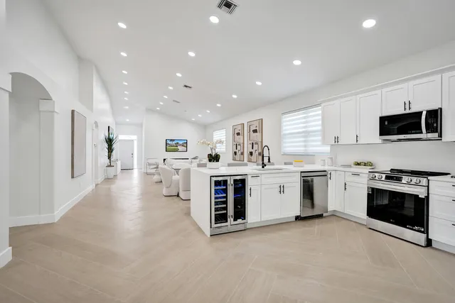 a large kitchen with stainless steel appliances a large counter top a stove and a sink