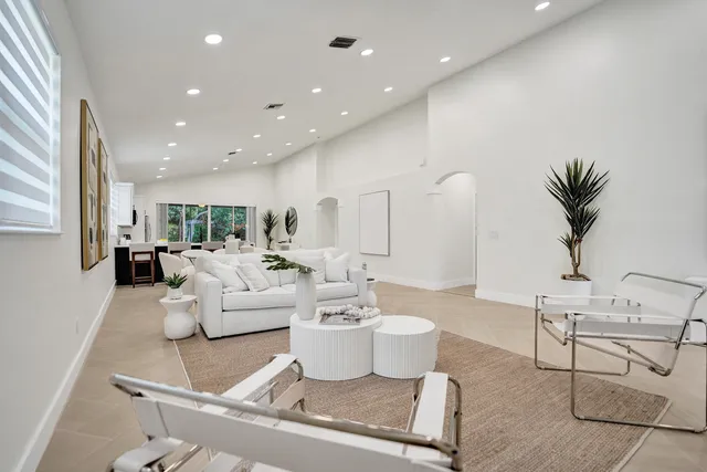 a kitchen with stainless steel appliances a sink a microwave a refrigerator white cabinets and a potted plant