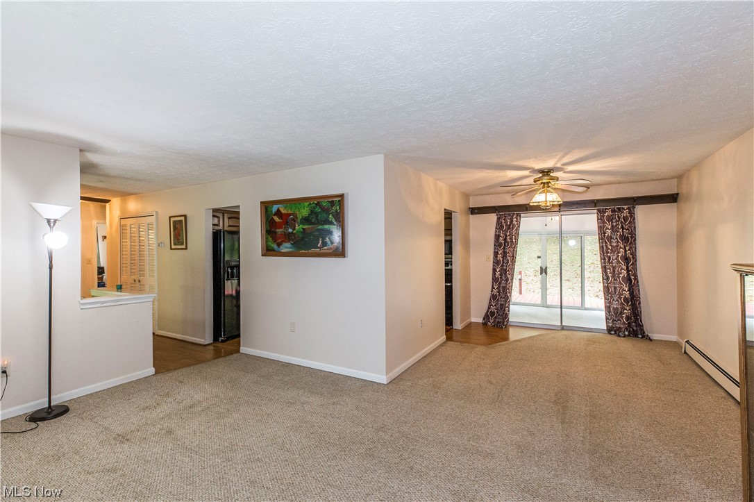 3077 Luli Road Mogadore, OH 44260 - Photo 6 of 34 Carpeted empty room featuring ceiling fan, a baseboard heating unit, and a textured ceiling