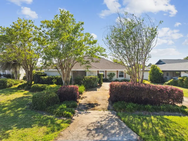 a front view of a house with a garden and trees