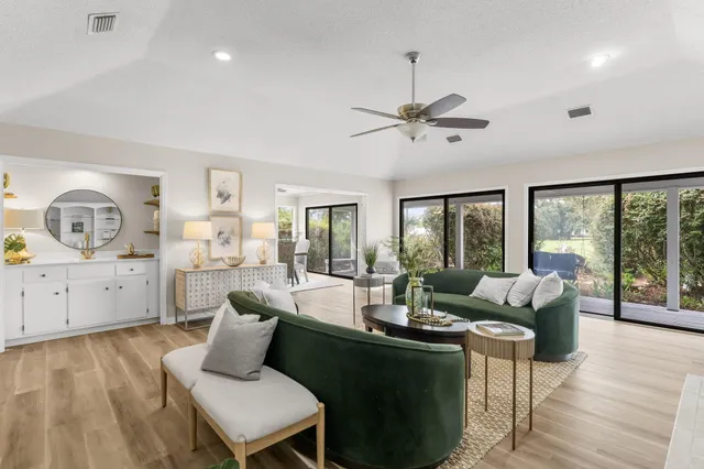 a living room with furniture large window and wooden floor