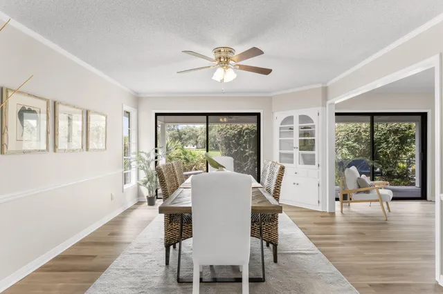 a dining room with wooden floor a chandelier a glass table and windows
