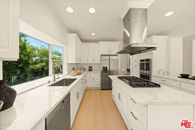 a kitchen with a stove a sink a refrigerator and windows