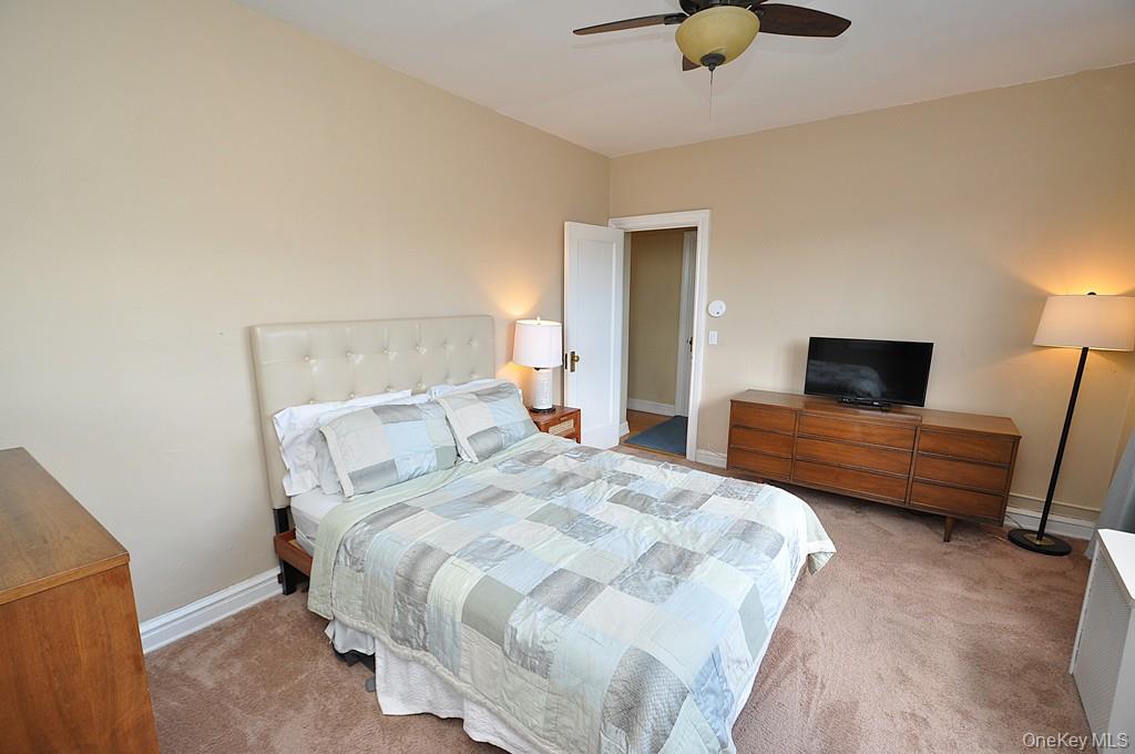143 Garth Road, Unit 5J Scarsdale, NY 10583 - Photo 20 of 47 a bedroom with a bed a couch and a flat screen tv