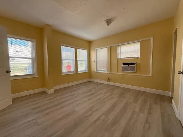 a view of an empty room with window and wooden floor