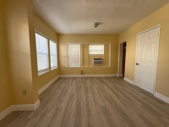 a view of an empty room with wooden floor and a window