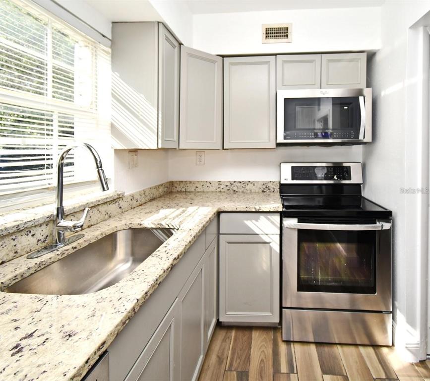 3057 Aaron Burr Avenue, Unit 1 Winter Park, FL 32792 - Photo 2 of 11 a kitchen with granite countertop a sink a stove and microwave