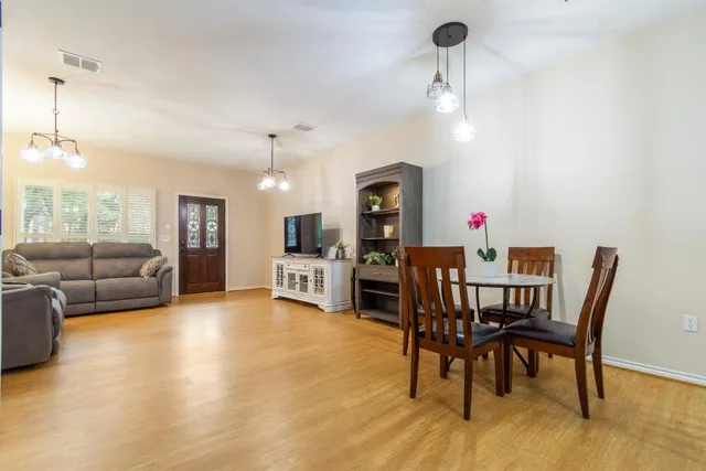 a kitchen with stainless steel appliances kitchen island granite countertop a refrigerator a stove a kitchen island with chairs and wooden floor