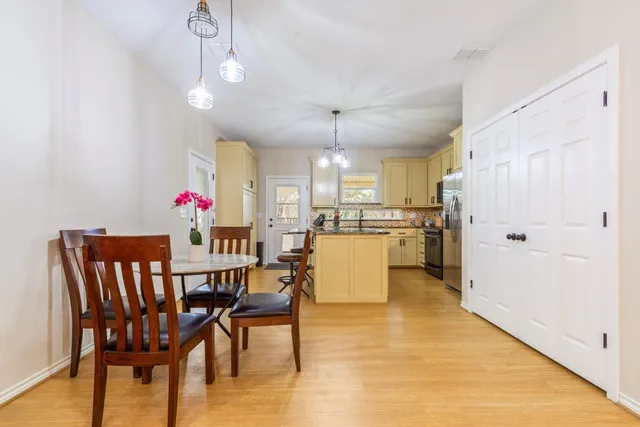 a kitchen with stainless steel appliances granite countertop a stove a refrigerator a kitchen island a dining table and chairs with wooden floor