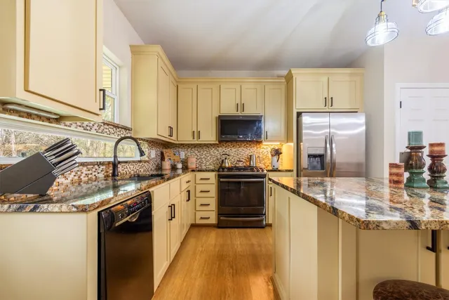 a kitchen with stainless steel appliances granite countertop a sink refrigerator and cabinets