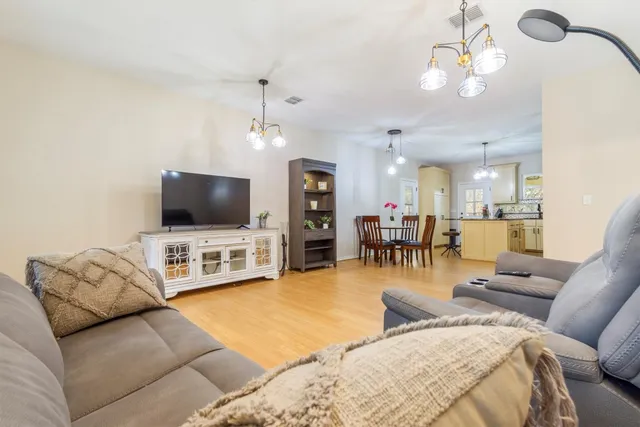 a view of a dining room and livingroom with furniture wooden floor a chandelier