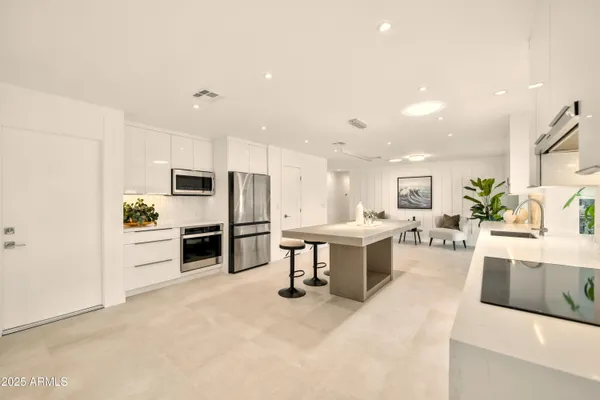 a large kitchen with kitchen island a sink a stove a refrigerator and a dining table with wooden floor