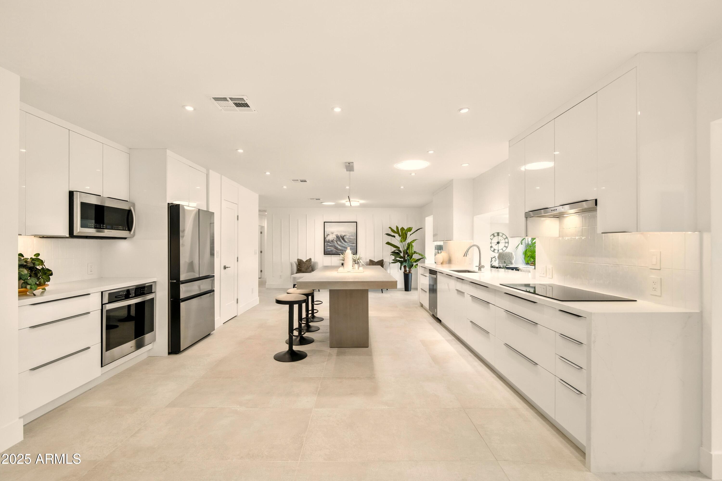 2425 West Impala Circle Mesa, AZ 85202 - Photo 17 of 55 a large kitchen with kitchen island a sink a stove a refrigerator and a dining table with wooden floor