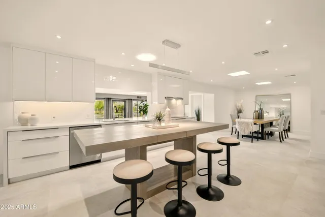 a large kitchen with kitchen island white cabinets and stainless steel appliances