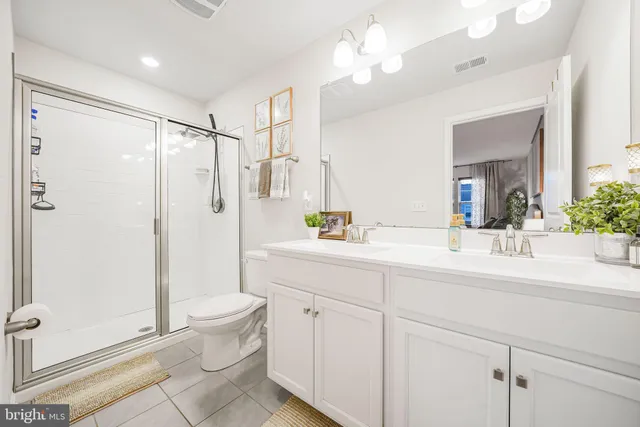 a bathroom with a double vanity sink toilet mirror and shower