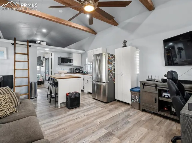 a living room with furniture a flat screen tv and kitchen view