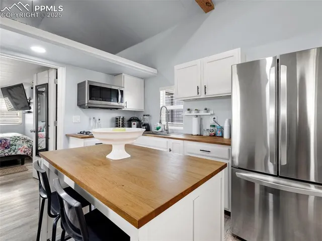 a kitchen with kitchen island a stove a sink a refrigerator and a dining table