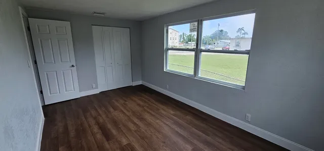 a view of an empty room with wooden floor and a window