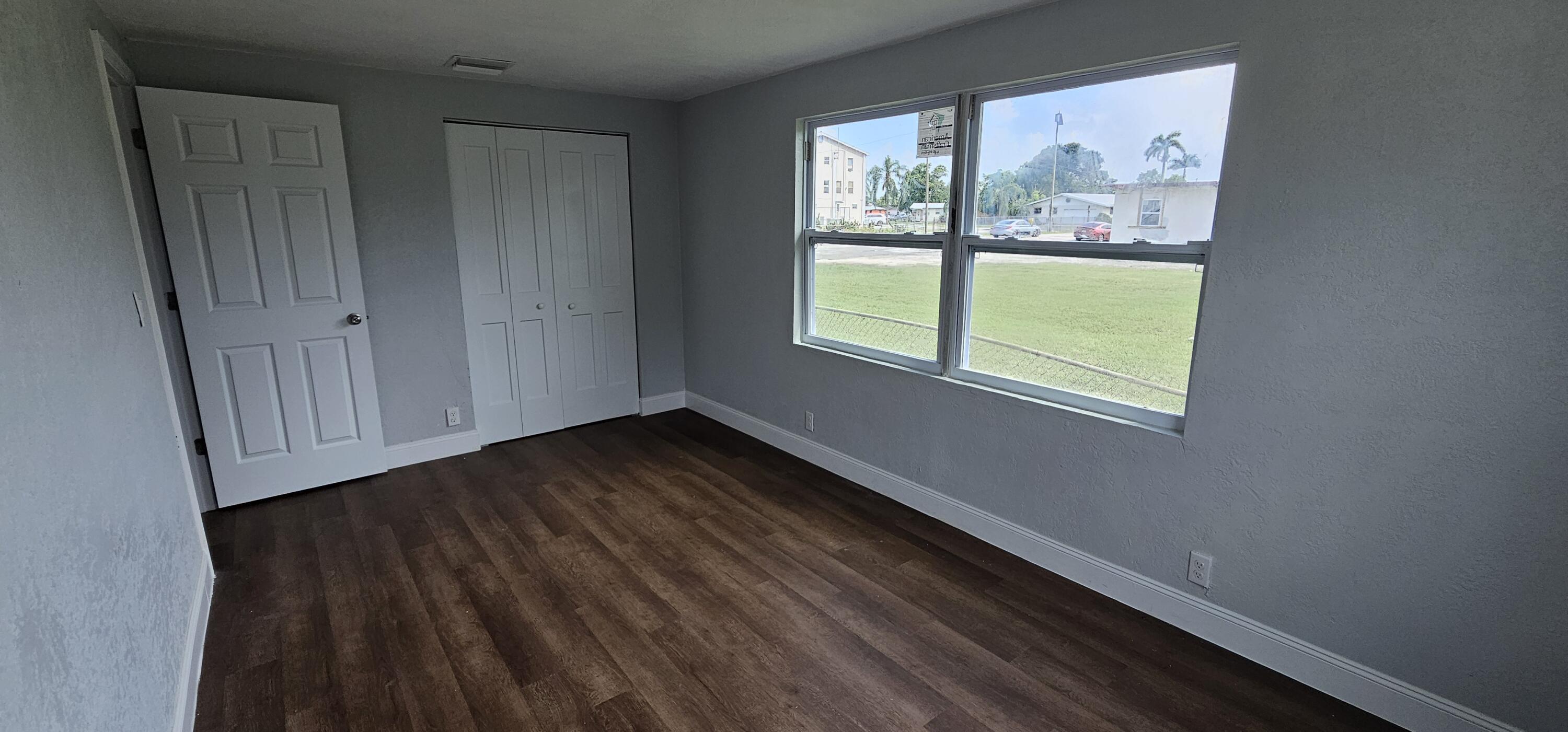 540 Southwest 9th Street Belle Glade, FL 33430 - Photo 17 of 28 a view of an empty room with wooden floor and a window