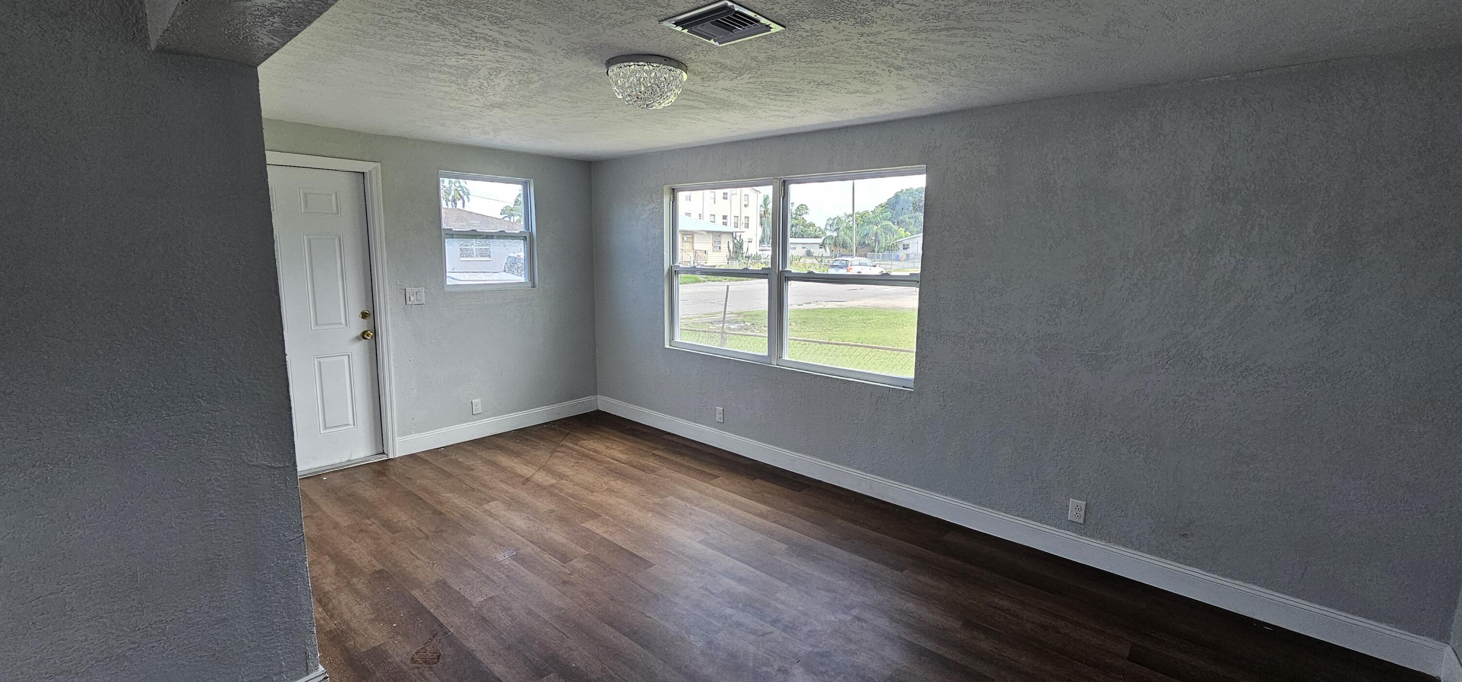 540 Southwest 9th Street Belle Glade, FL 33430 - Photo 4 of 28 an empty room with wooden floor and windows