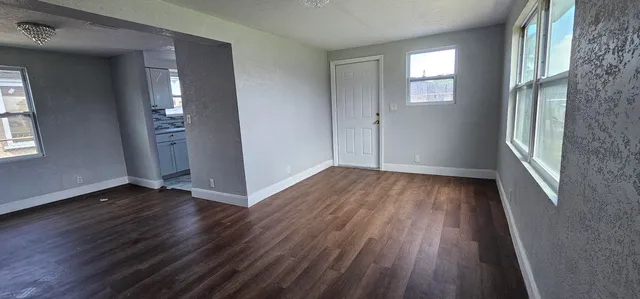 an empty room with wooden floor and windows