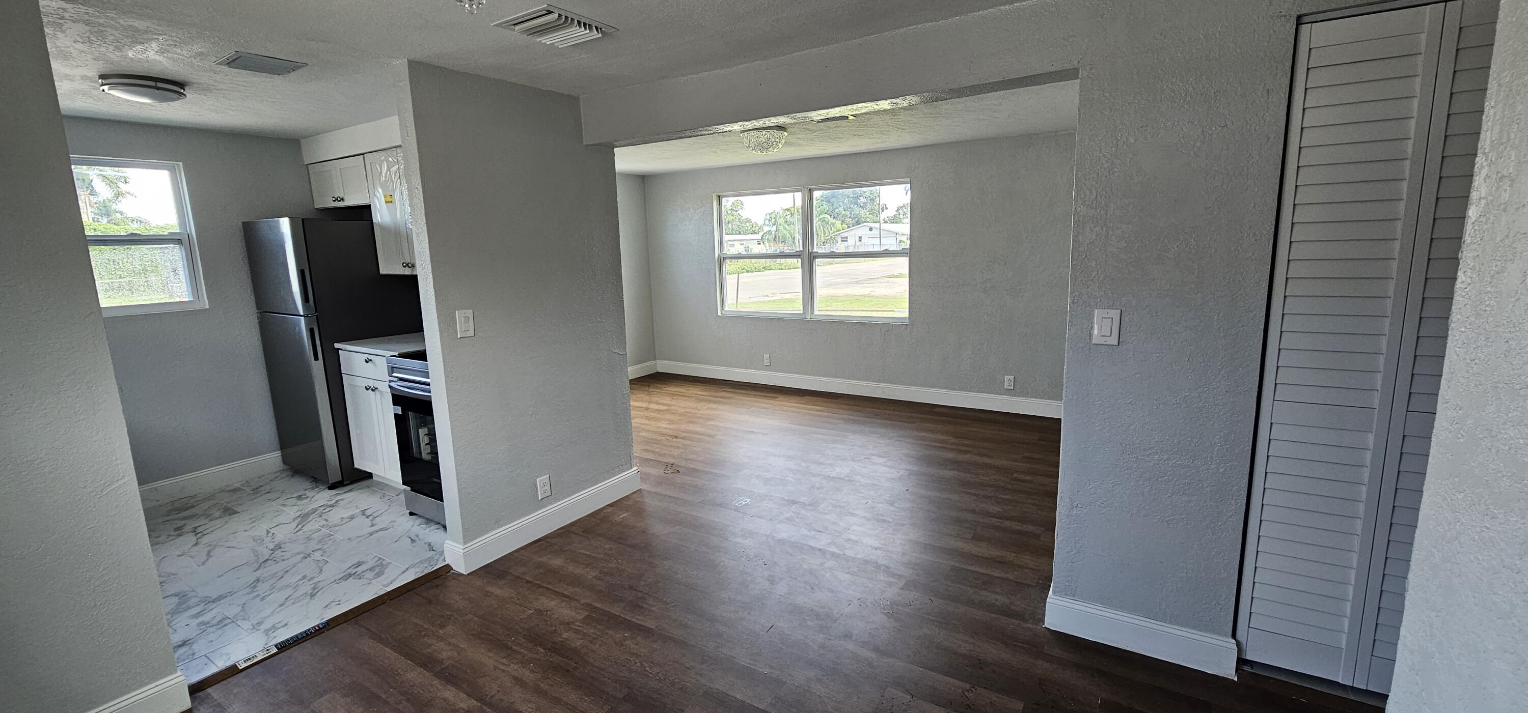 540 Southwest 9th Street Belle Glade, FL 33430 - Photo 8 of 28 a view of a hallway with wooden floor and a flat screen tv