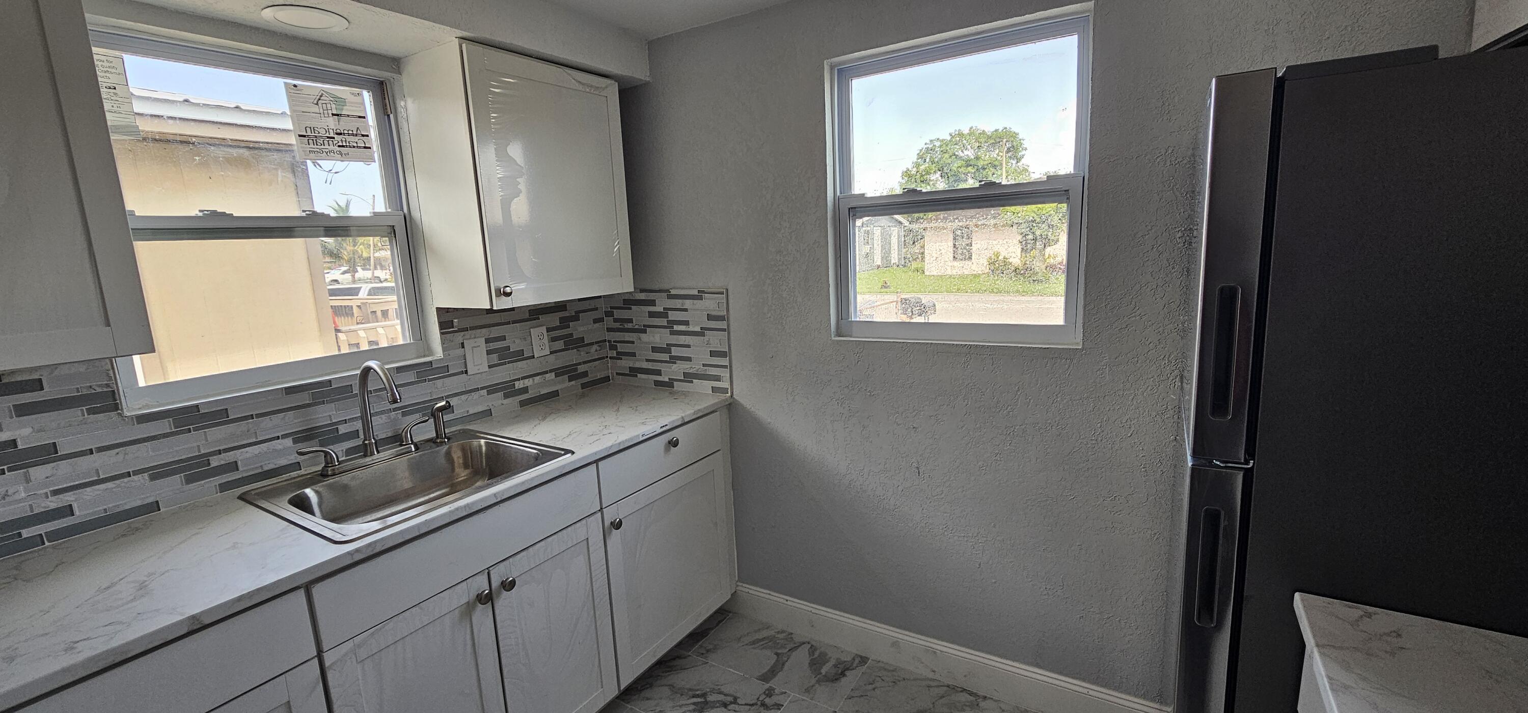 540 Southwest 9th Street Belle Glade, FL 33430 - Photo 10 of 28 a kitchen with a sink window and cabinets