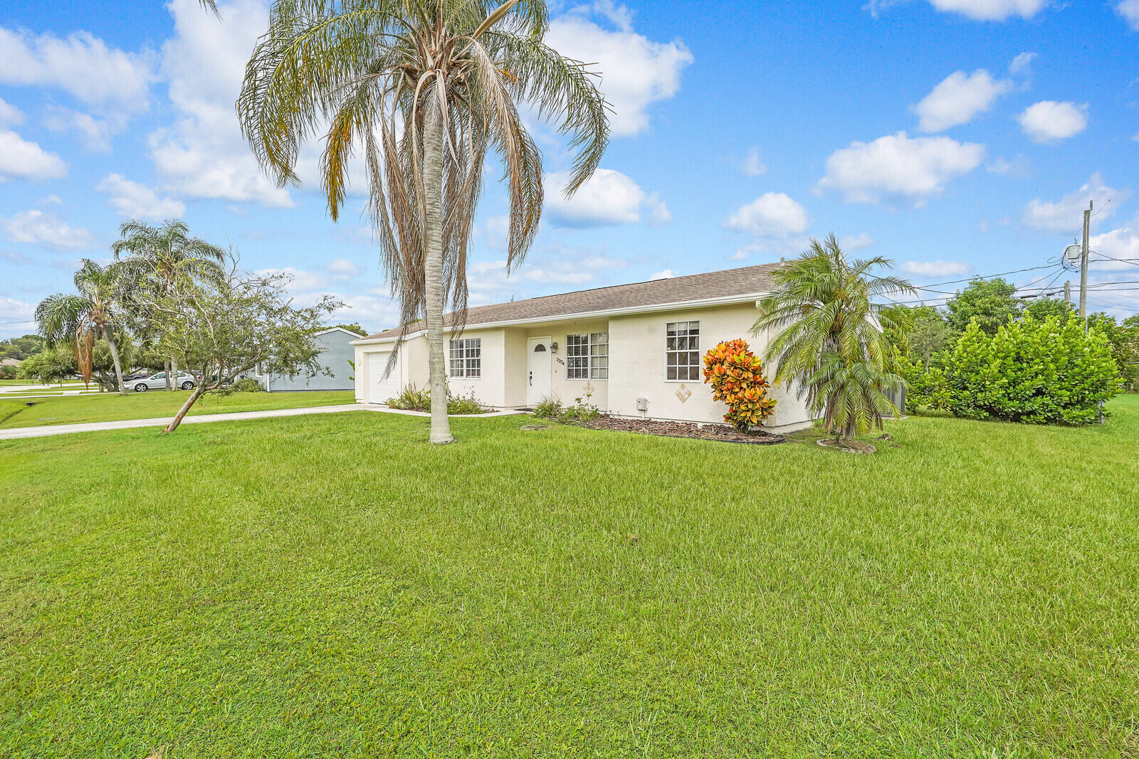 2334 Southeast Merrill Road Port St. Lucie, FL 34952 - Photo 2 of 27 a view of a house with a big yard and palm trees