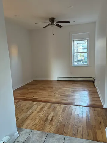an empty room with wooden floor a ceiling fan and windows