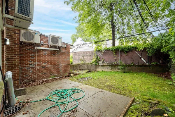 a backyard of a house with yard plants and large tree