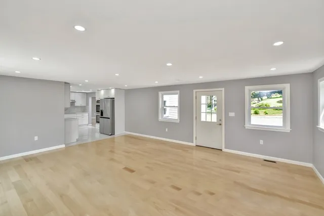 a view of an empty room with window and wooden floor