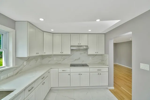 a kitchen with white cabinets granite counter tops and a stove