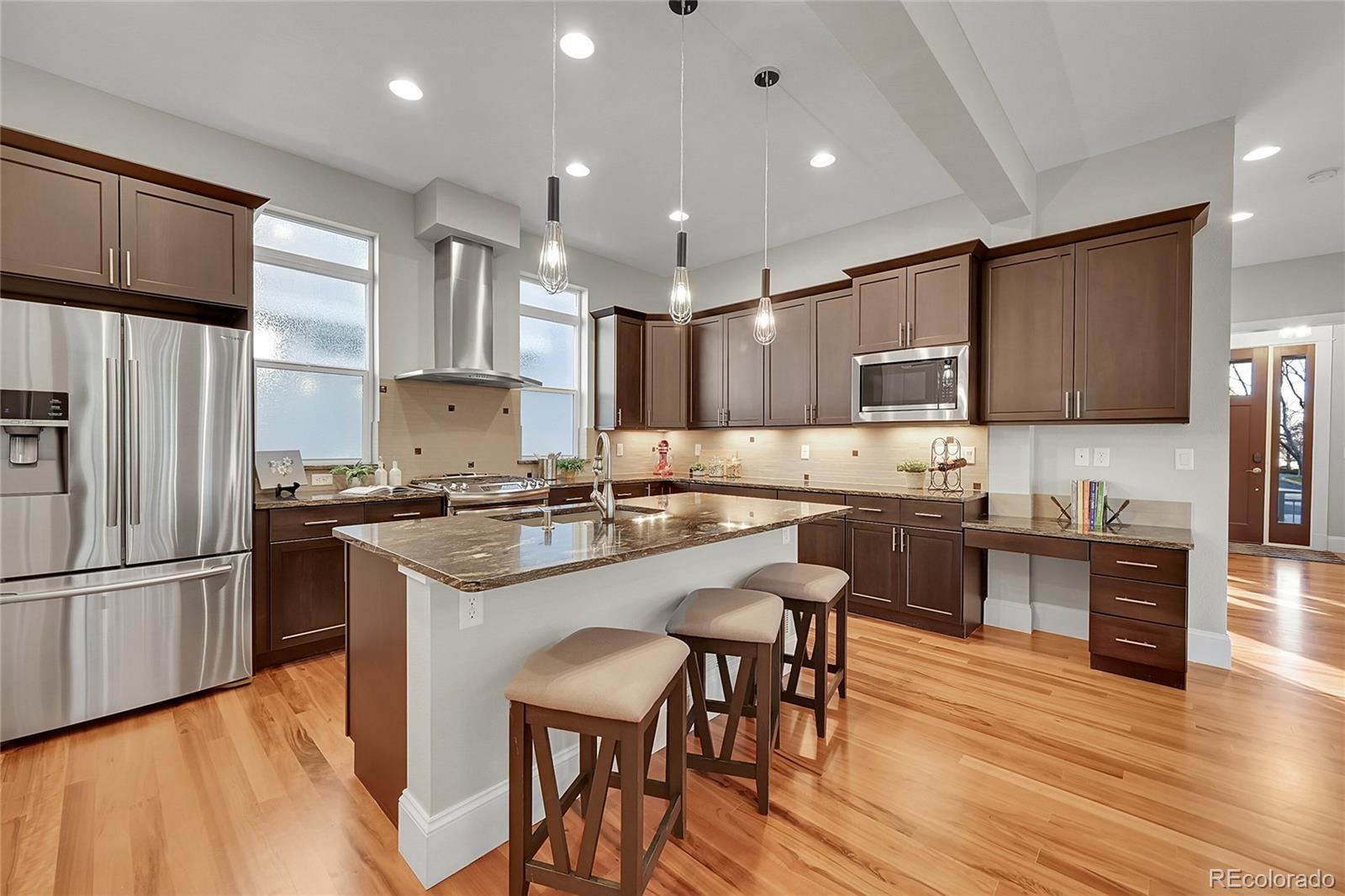 3693 Silverton Street Boulder, CO 80301 - Photo 12 of 50 a kitchen with kitchen island granite countertop wooden floors white cabinets and stainless steel appliances