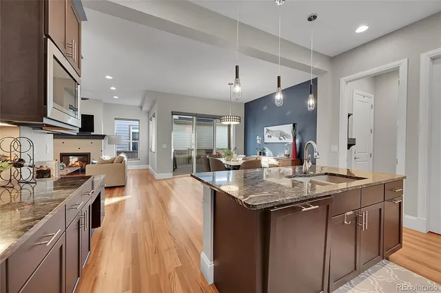 a kitchen with stainless steel appliances granite countertop a sink dishwasher stove refrigerator and cabinets with wooden floor