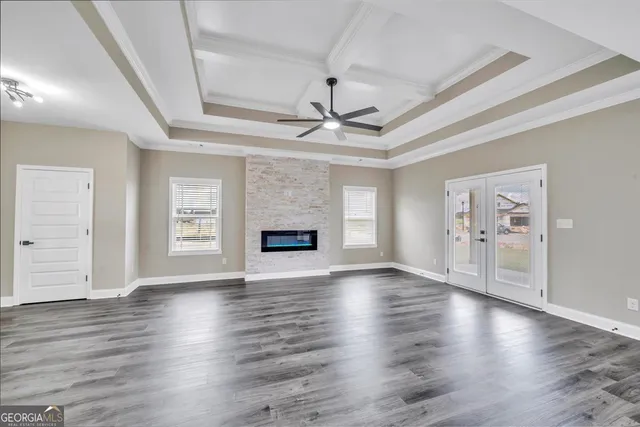an empty room with wooden floor a ceiling fan and windows