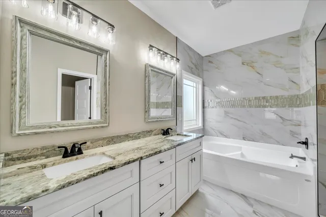 a bathroom with a granite countertop tub sink and mirror