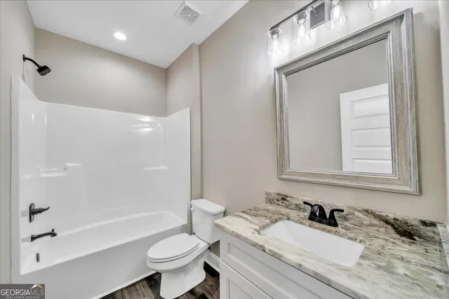 a bathroom with a granite countertop sink toilet a large mirror a bathtub and shower