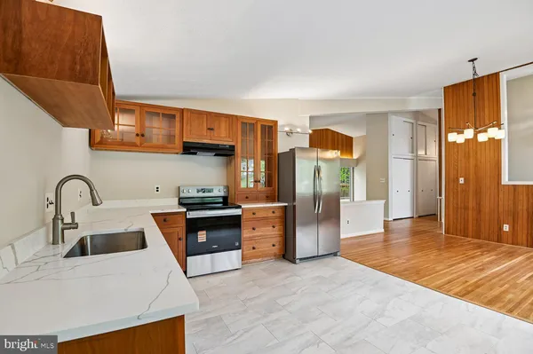 a large white kitchen with stainless steel appliances granite countertop a stove and a sink