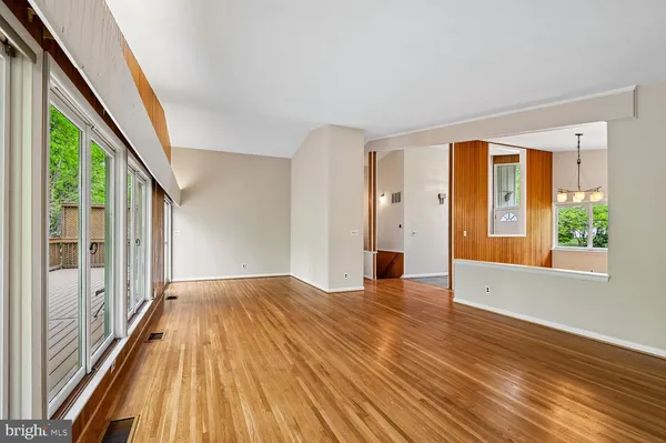 a view of a hallway with wooden floor and a bathroom