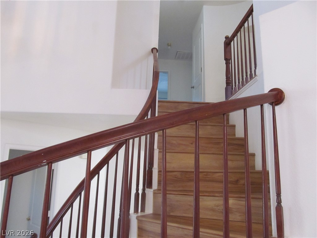 8701 Crescent Ridge Lane Las Vegas, NV 89134 - Photo 17 of 28 Rich hardwood stairs ascend gracefully, featuring traditional wooden railings.
