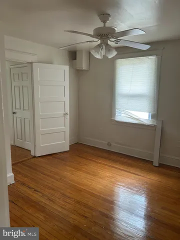 an empty room with wooden floor cabinet and windows