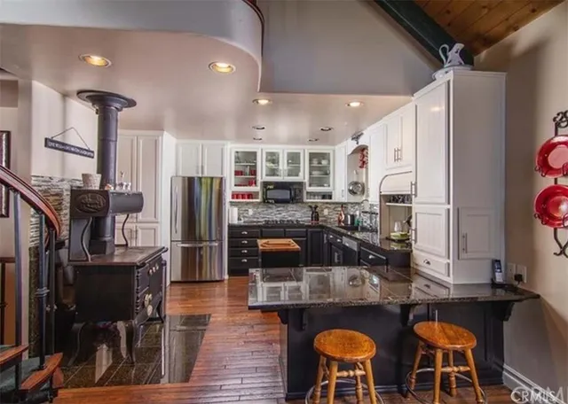 a kitchen with stainless steel appliances granite countertop a stove top oven a refrigerator and chairs