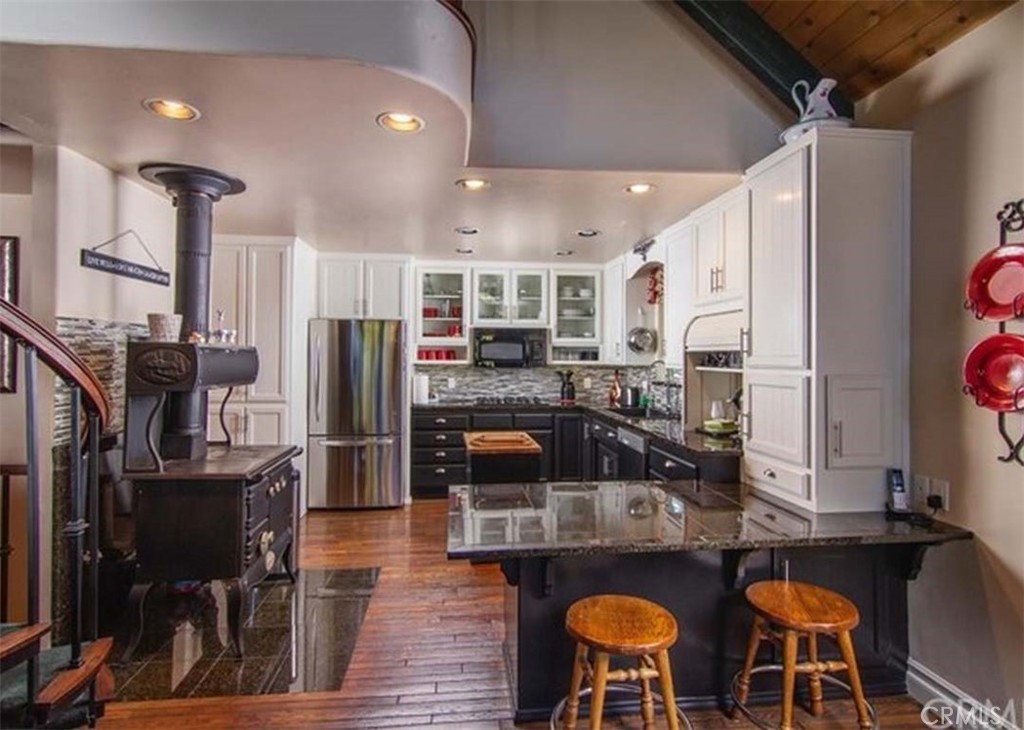 a kitchen with stainless steel appliances granite countertop a stove top oven a refrigerator and chairs