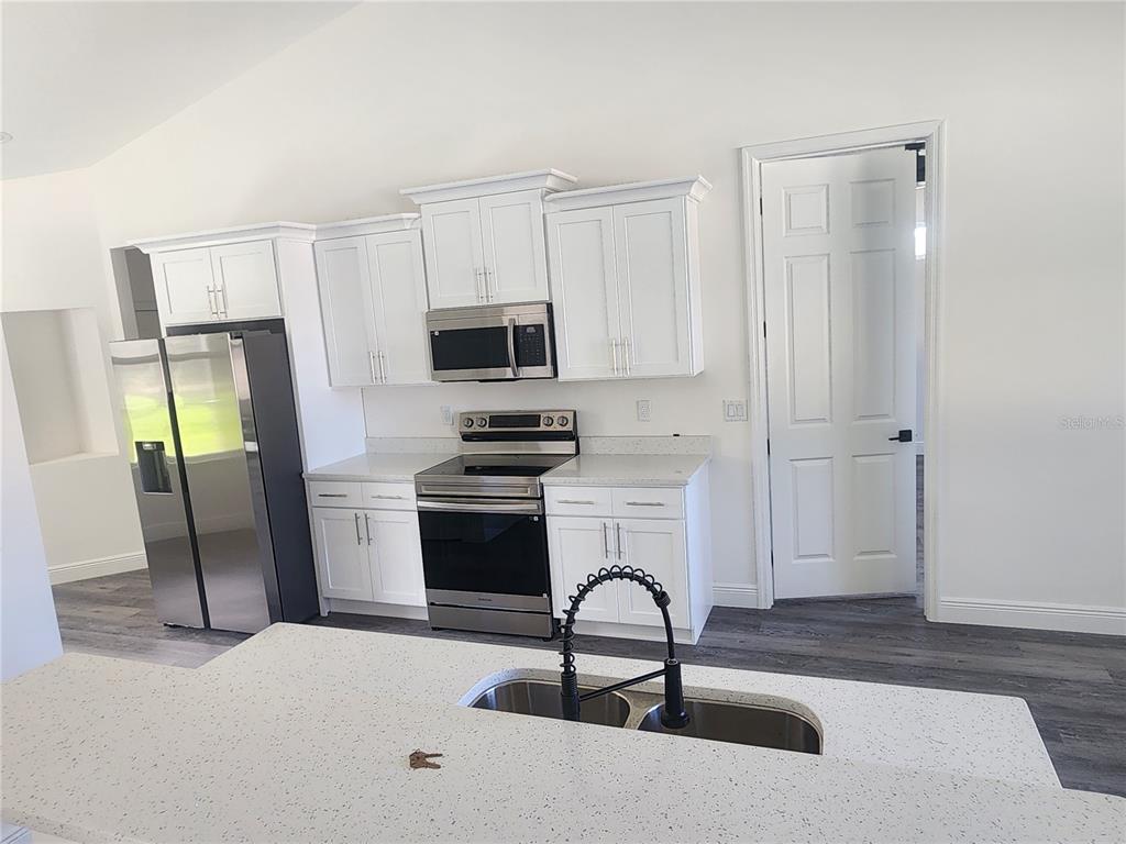 9483 Southwest 121st Terrace Dunnellon, FL 34432 - Photo 17 of 42 a kitchen with a refrigerator a sink and a stove top oven